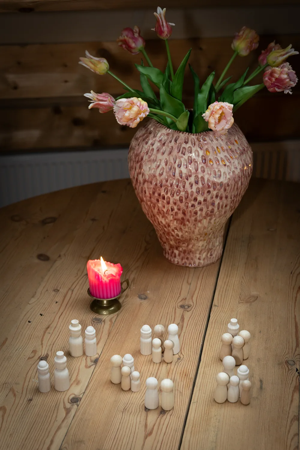 Houten poppetjes in groepjes op tafel bij een brandende kaars