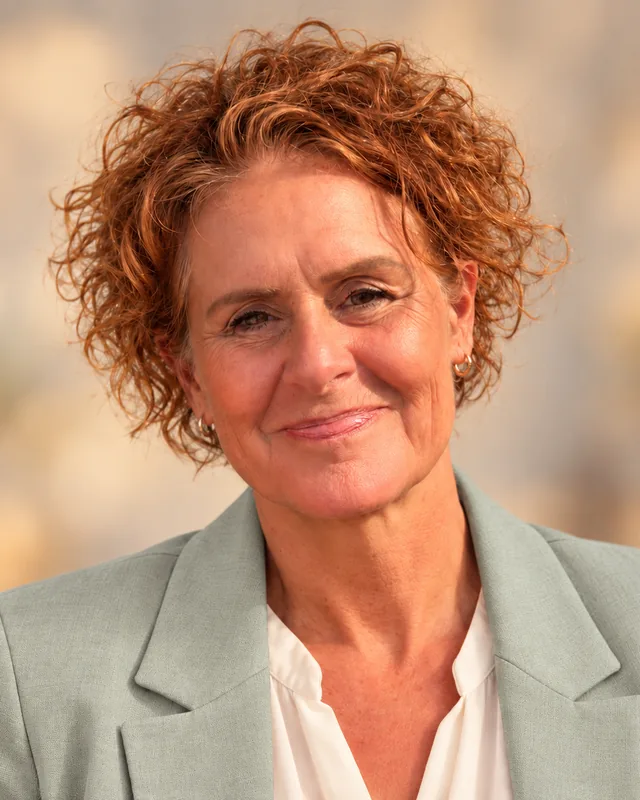 Portret van Anita Hols-de Bruin, glimlachend in een saliegroen colbert
